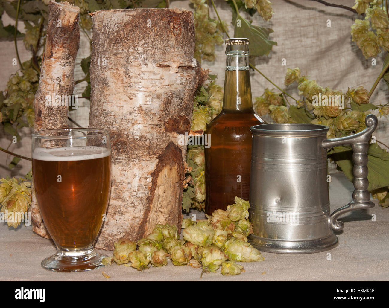 Homebrew home made beer in bottle and glass with fresh hops pewter tankard and birch log Beverley, East Yorkshire, England Stock Photo