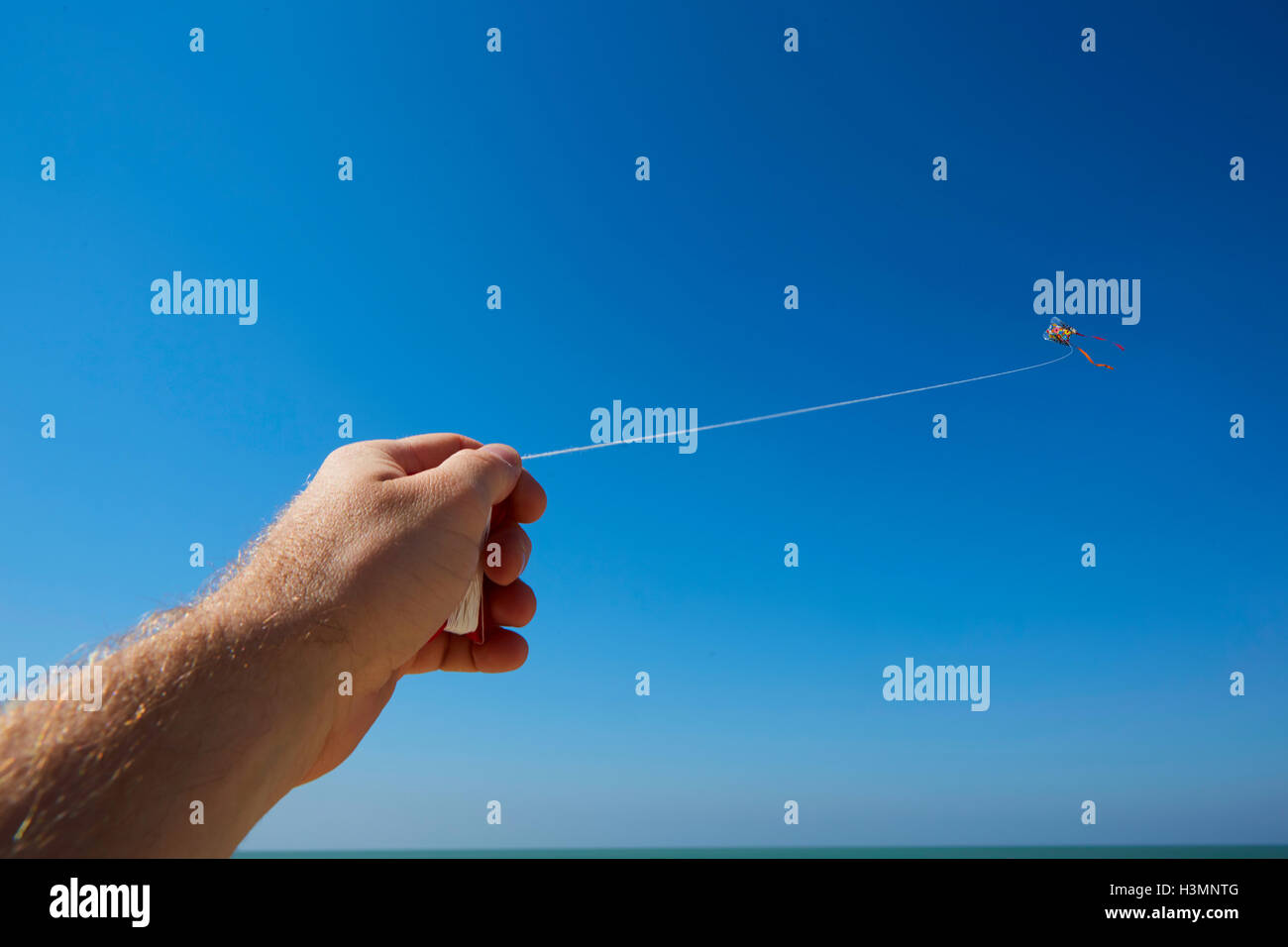 Male hand holding kite strings with a kite in sky Stock Photo - Alamy