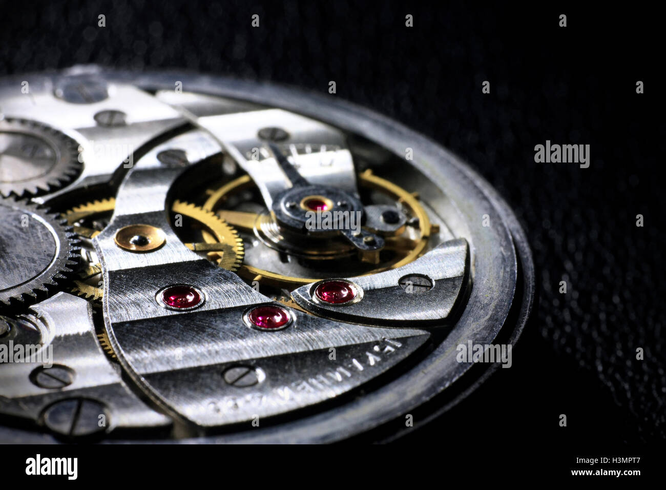 Pocket watch inside close up with wheels, springs and rubies on dark