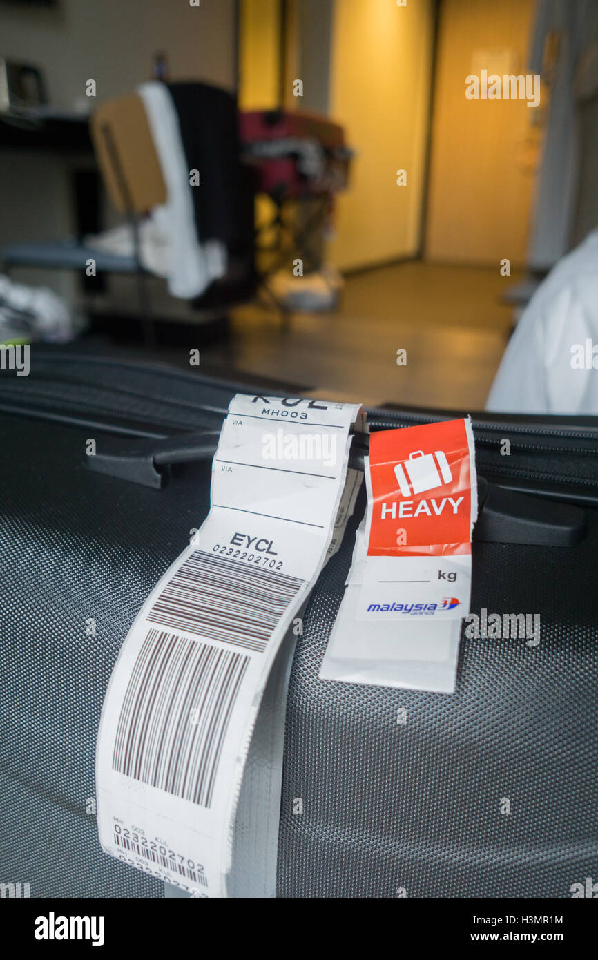Black suitcase with Malaysian Airlines baggage taggs one stating heavy  Stock Photo - Alamy