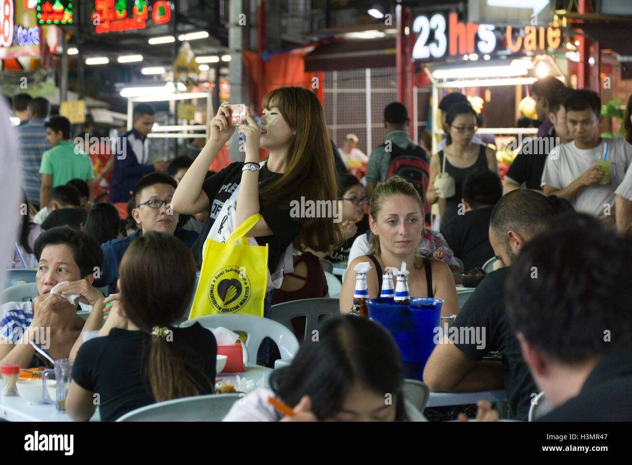 A young girl taking a photograph in the busy street food area of Jalan Alor,Kuala Lumpur,Malaysia, Stock Photo