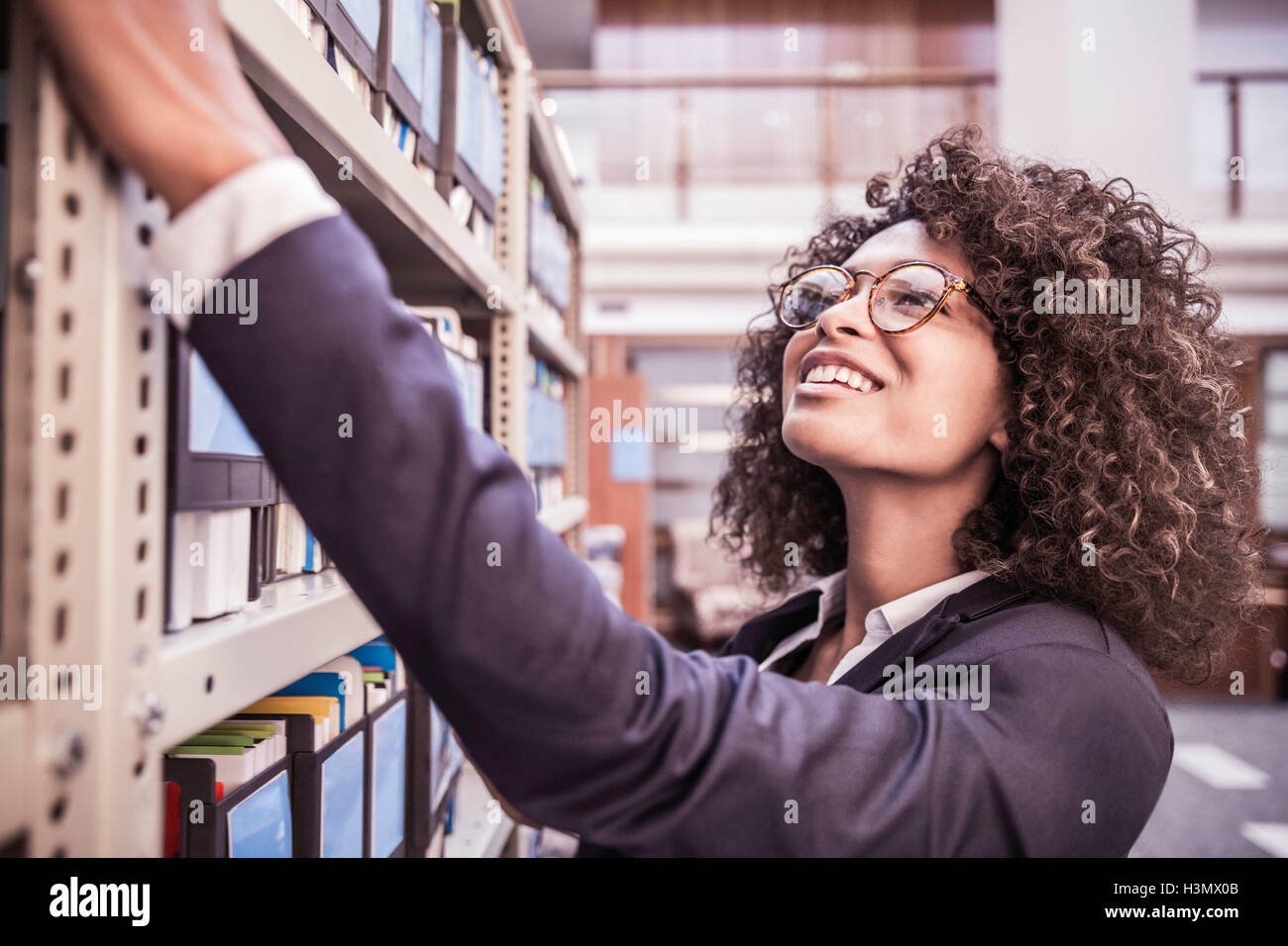 Young businesswoman searching office shelves Stock Photo