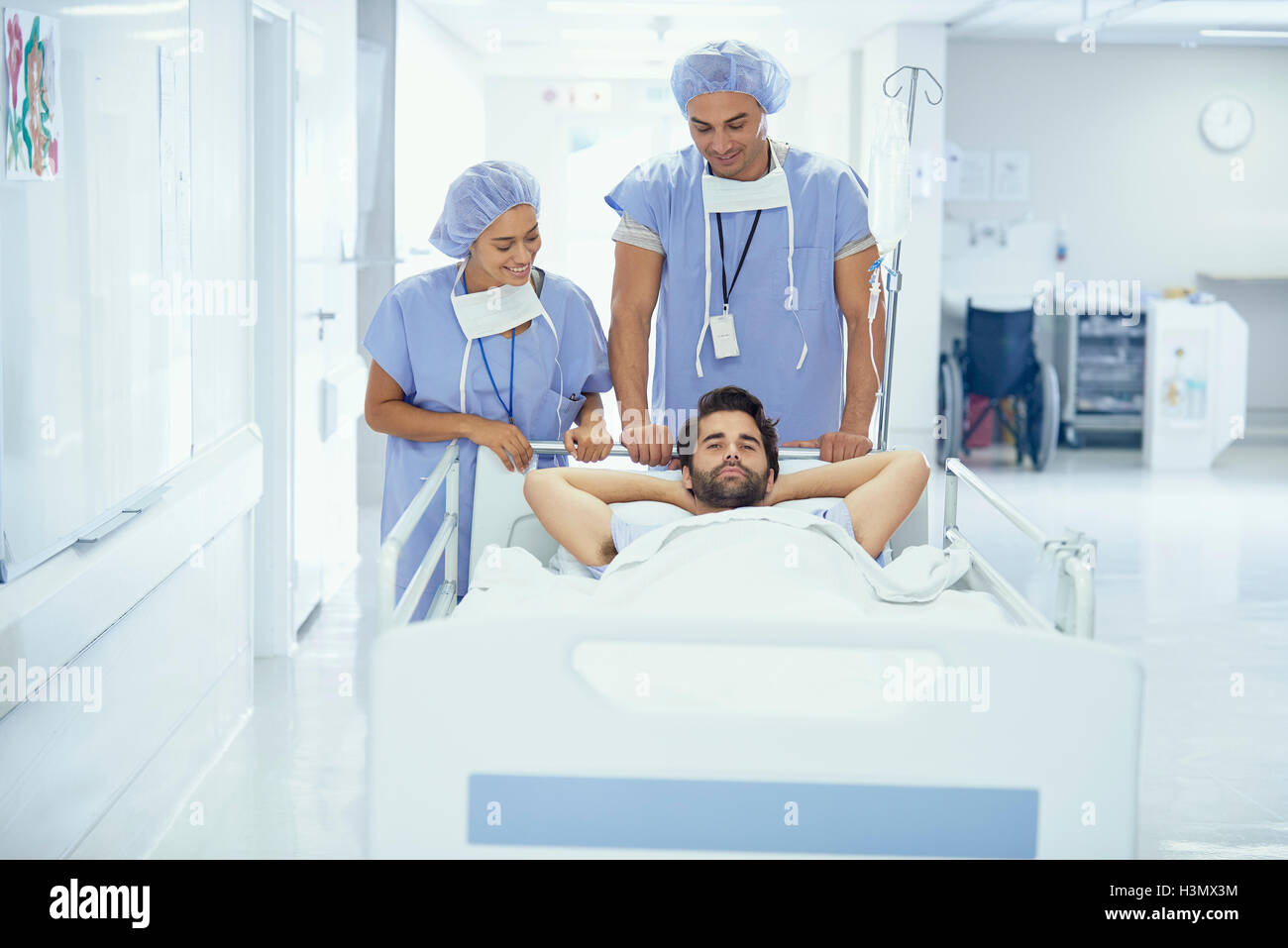 Young male patient in hospital bed being pushed by nurses Stock Photo