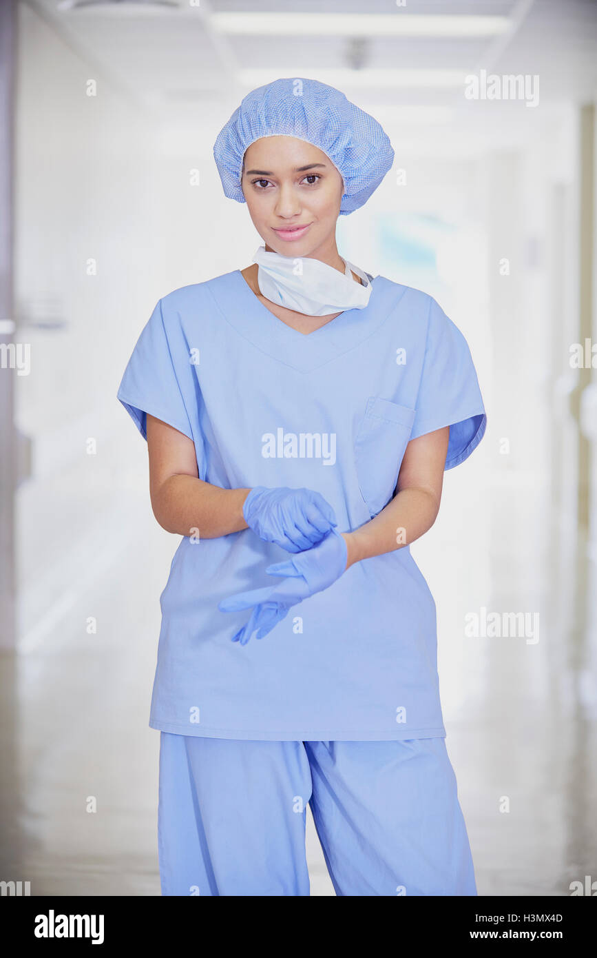 Portrait of mid adult female medic wearing scrubs in hospital corridor Stock Photo