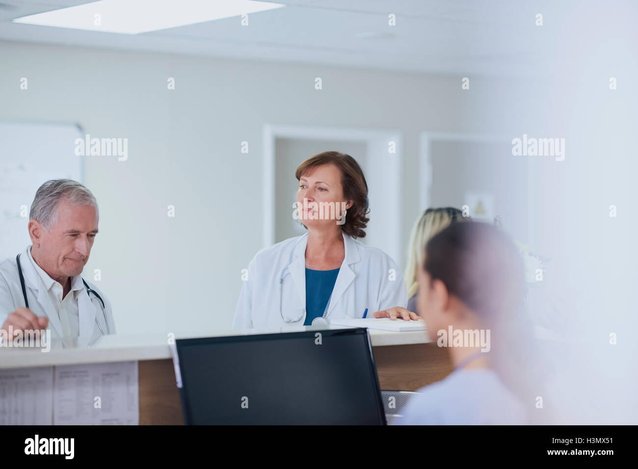 Senior male doctor thinking at nurses station in hospital Stock Photo