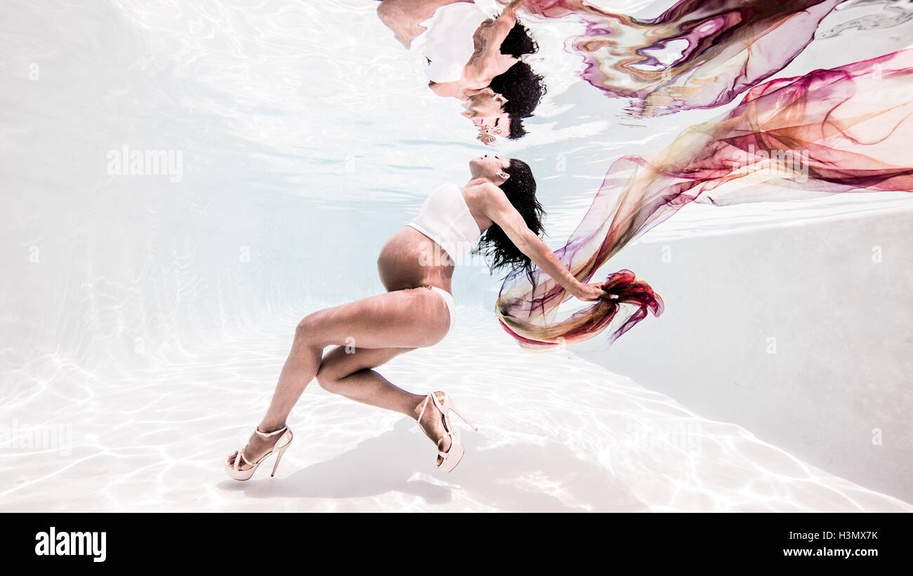 Underwater view of pregnant woman, face towards surface of water Stock Photo
