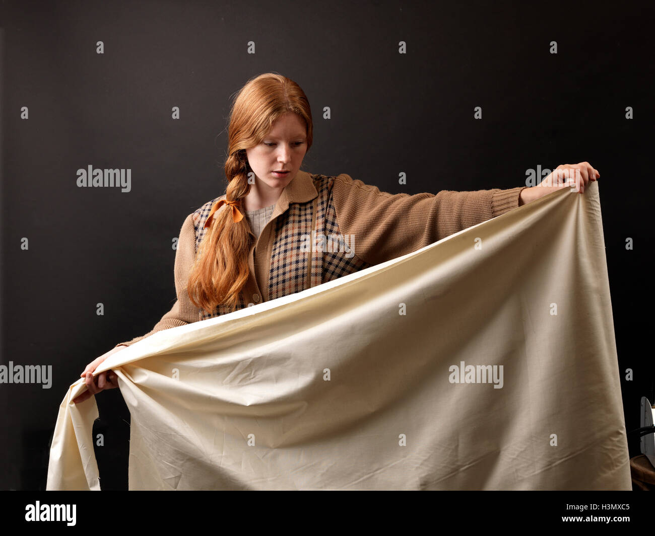 Young female designer inspecting rolled fabric Stock Photo