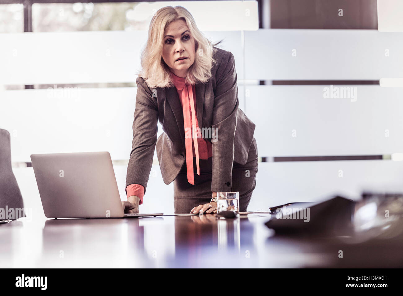 Determined businesswoman leaning forward on boardroom table Stock Photo