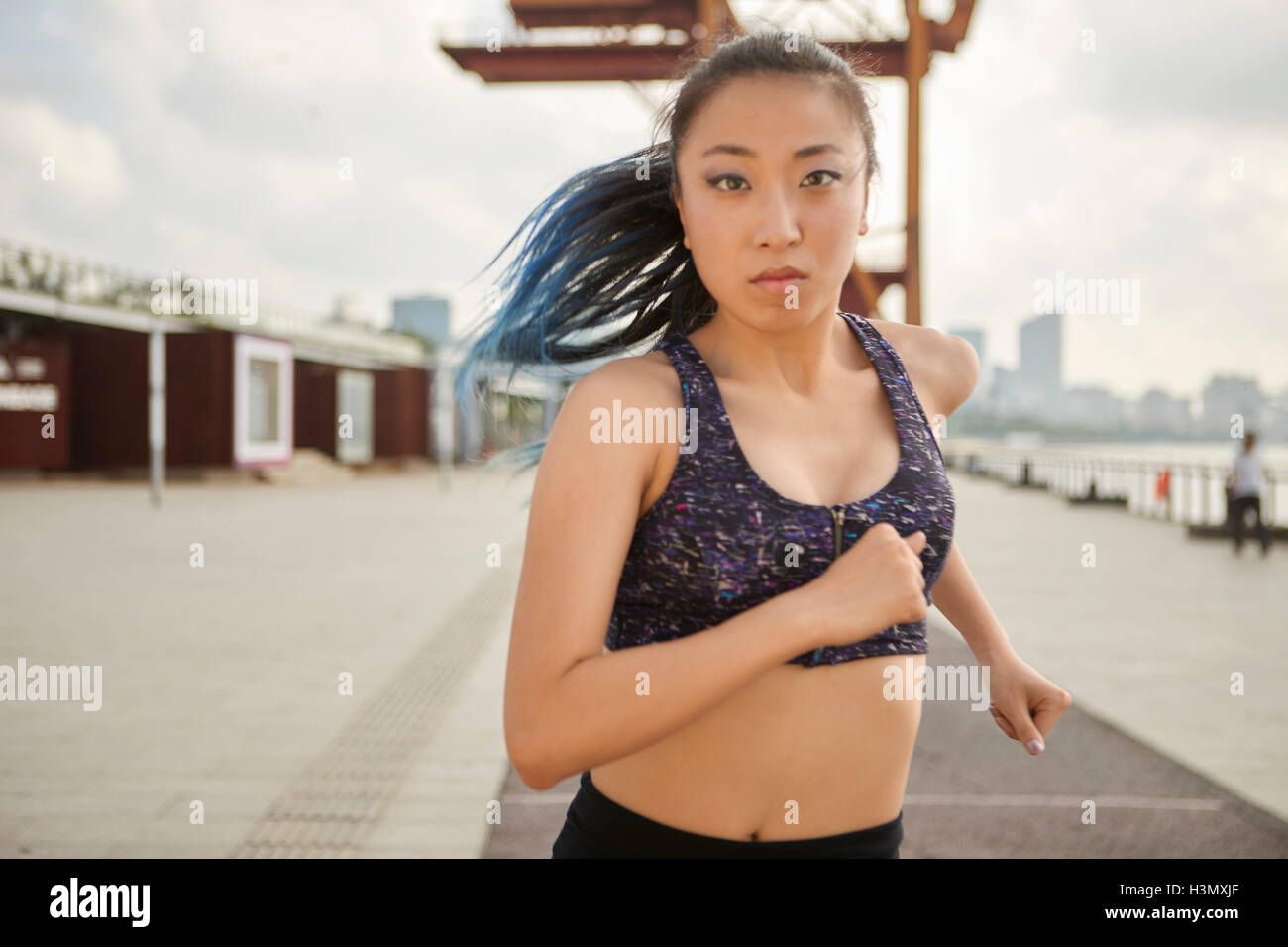 Woman jogging looking at camera, South Bund, Shanghai, China Stock Photo