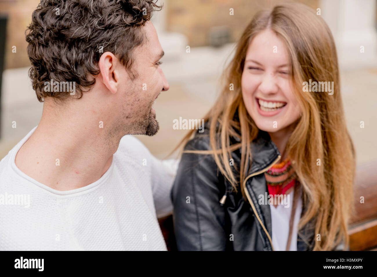 Happy young couple sitting on park bench Stock Photo - Alamy