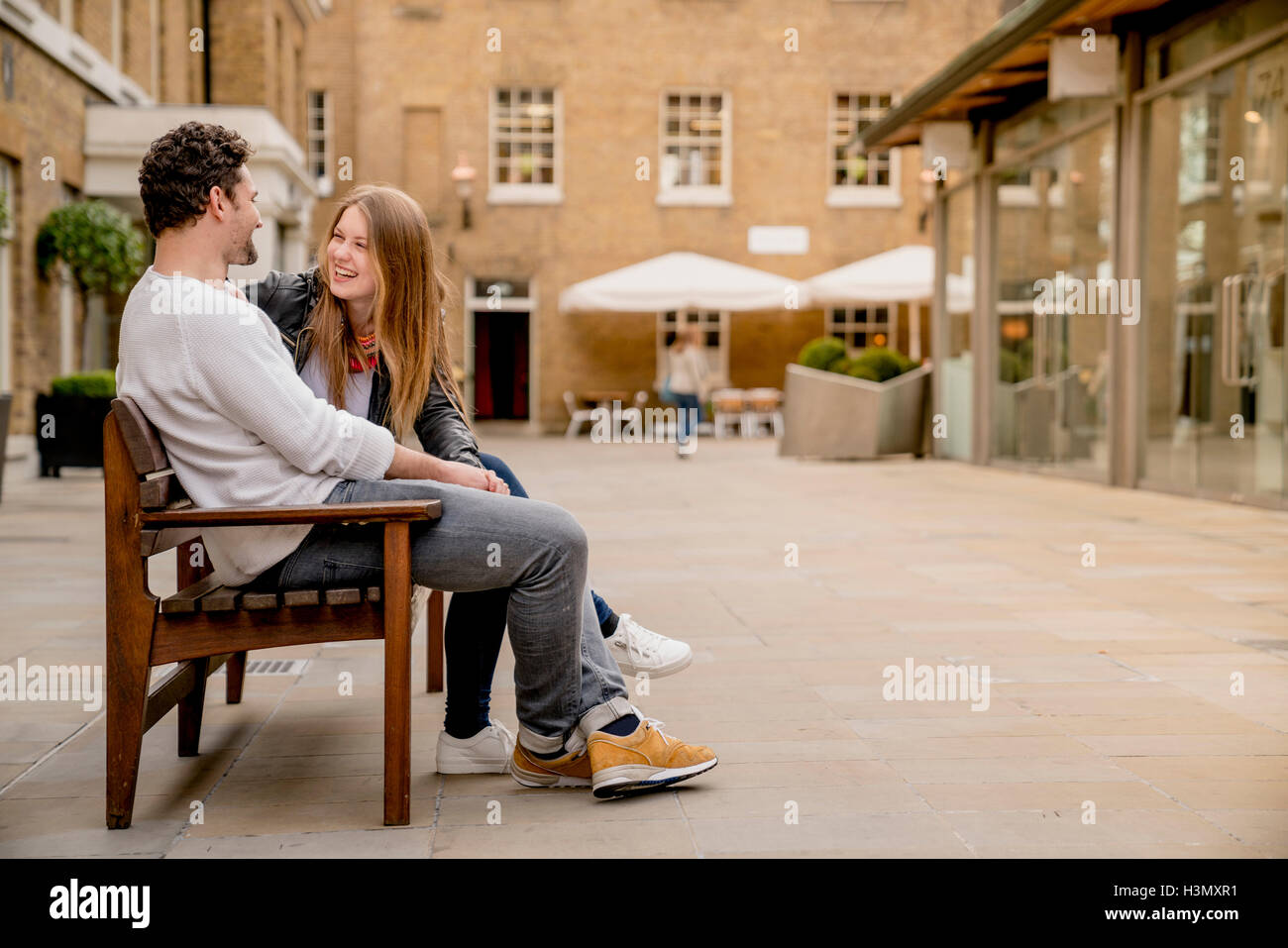 Young couple sitting on bench chatting, Kings Road, London, UK Stock Photo