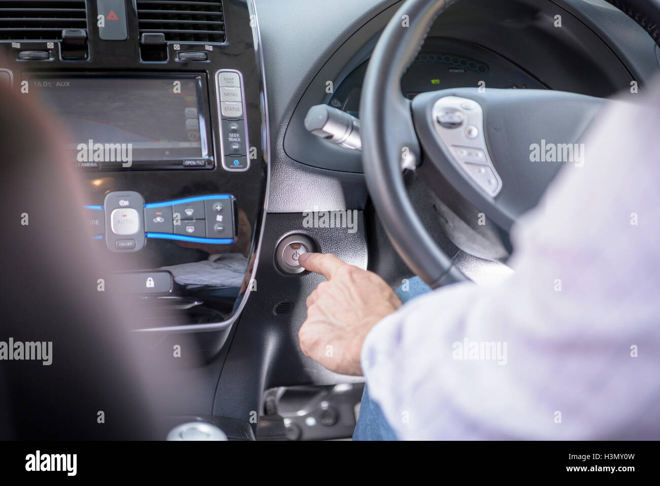 Man pressing start button on electric car, close up Stock Photo