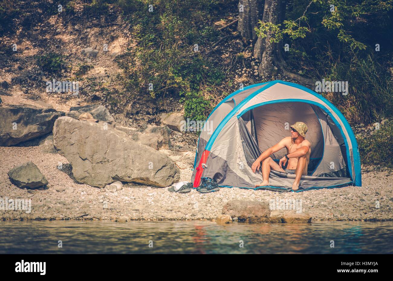 Tent Camping on the Rocky Lake Shore. Outdoor Men Lifestyle. Stock Photo
