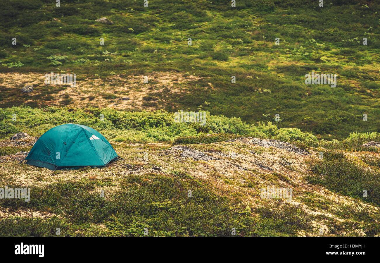 Tent Camping in the Wild. Small Tent on the Remote Mountain Landscape Meadow. Stock Photo
