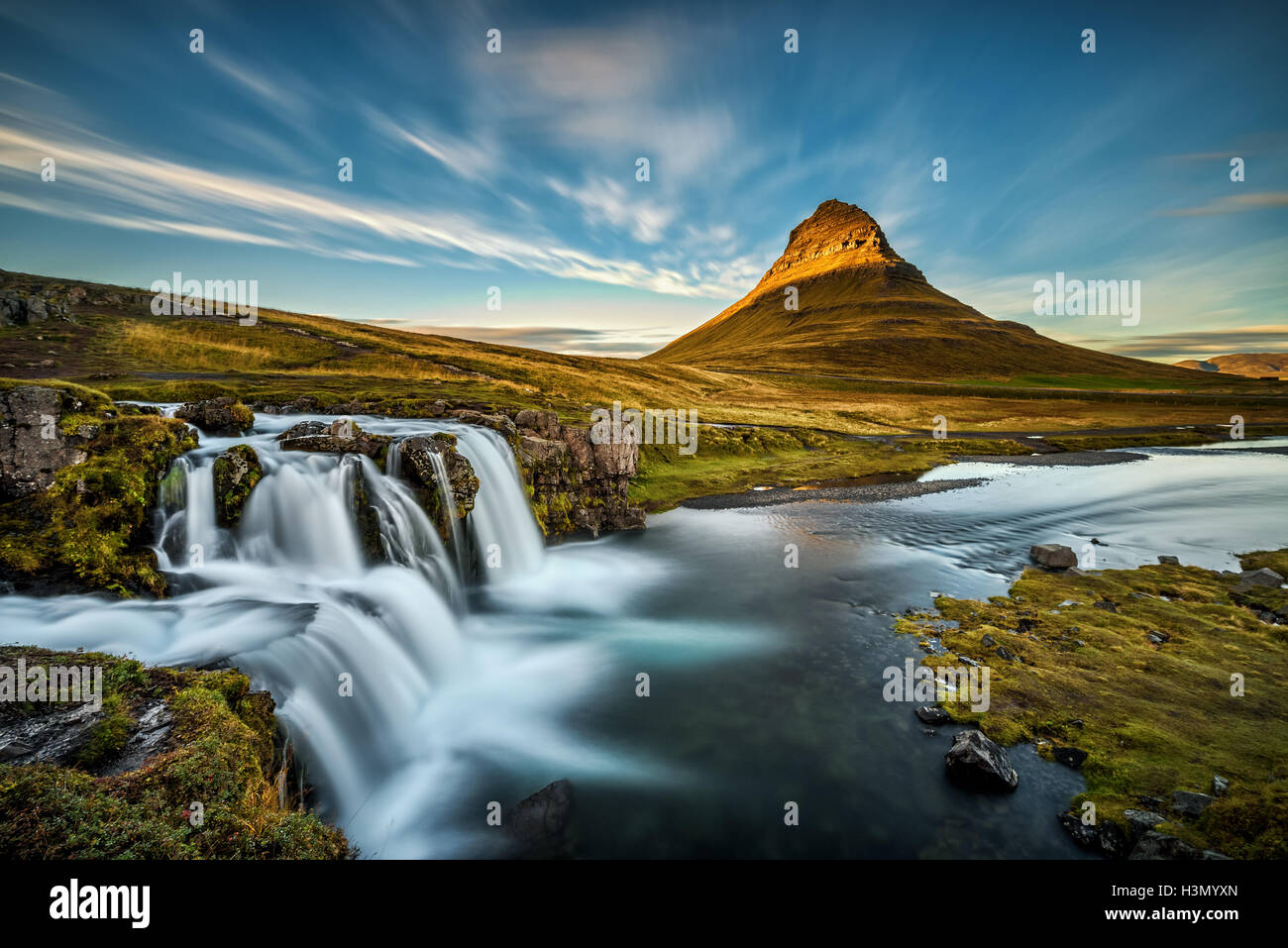 Summer sunset over the famous Kirkjufellsfoss Waterfall with Kirkjufell mountain in the background in Iceland. Long exposure. Stock Photo