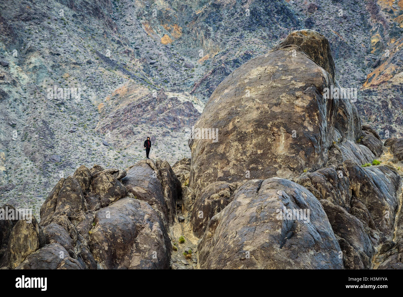 Climber is standing on the peak of rocks mountain at Racetrack Playa  in Death Valley National Park. Stock Photo