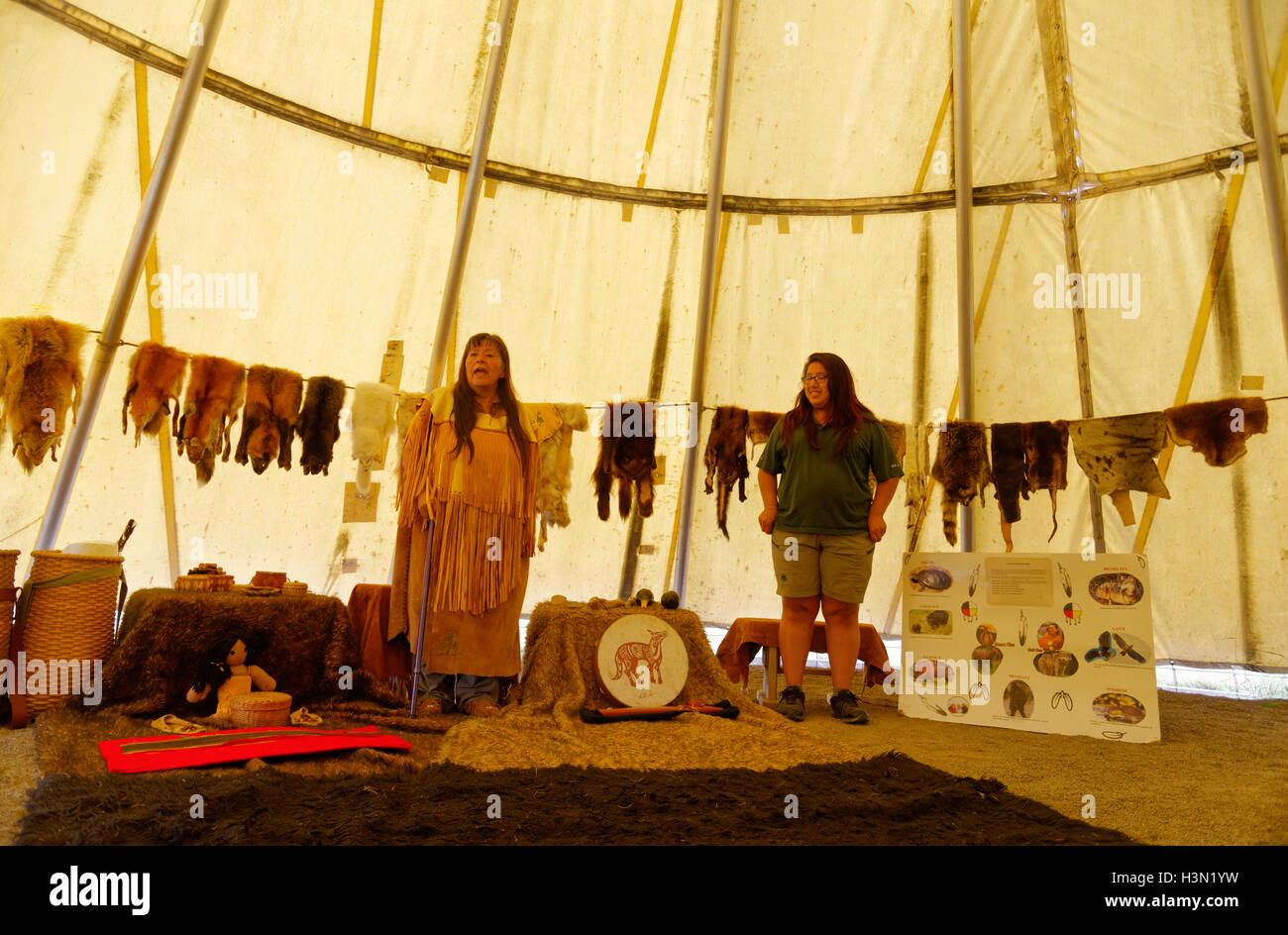 A native american (Micmac) woman speaking in a wigwam, with traditional objects & furs. Kouchibouguac NP New Brunswick Canada Stock Photo