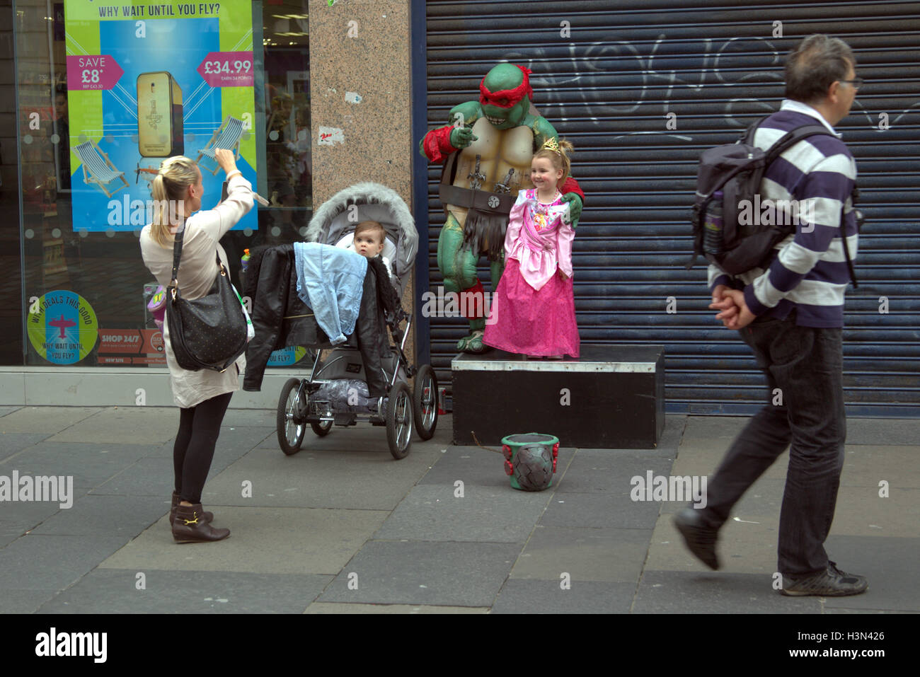 Glasgow street scenes family self portrait using fancy dress  street busker ninja turtle child as princess Stock Photo