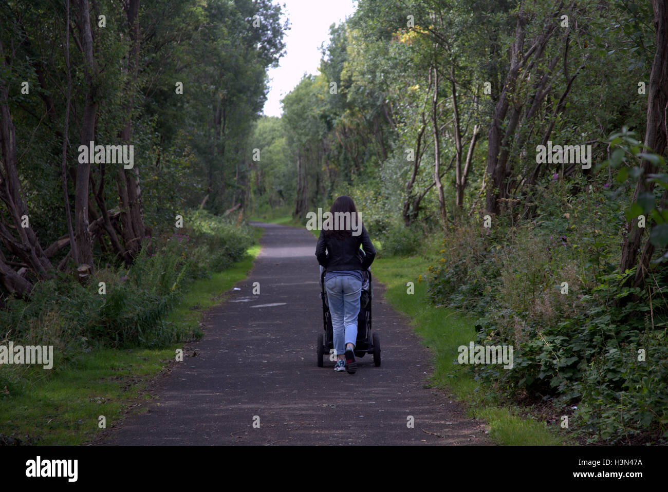 Glasgow park scenes girl pushing pram in park Stock Photo