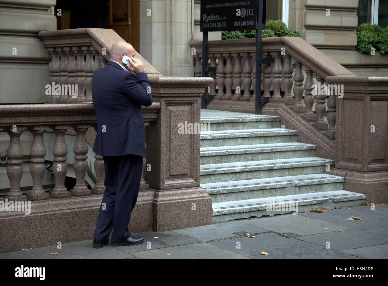 Glasgow street scenes businessman using mobile phone outside Victorian building steps Stock Photo