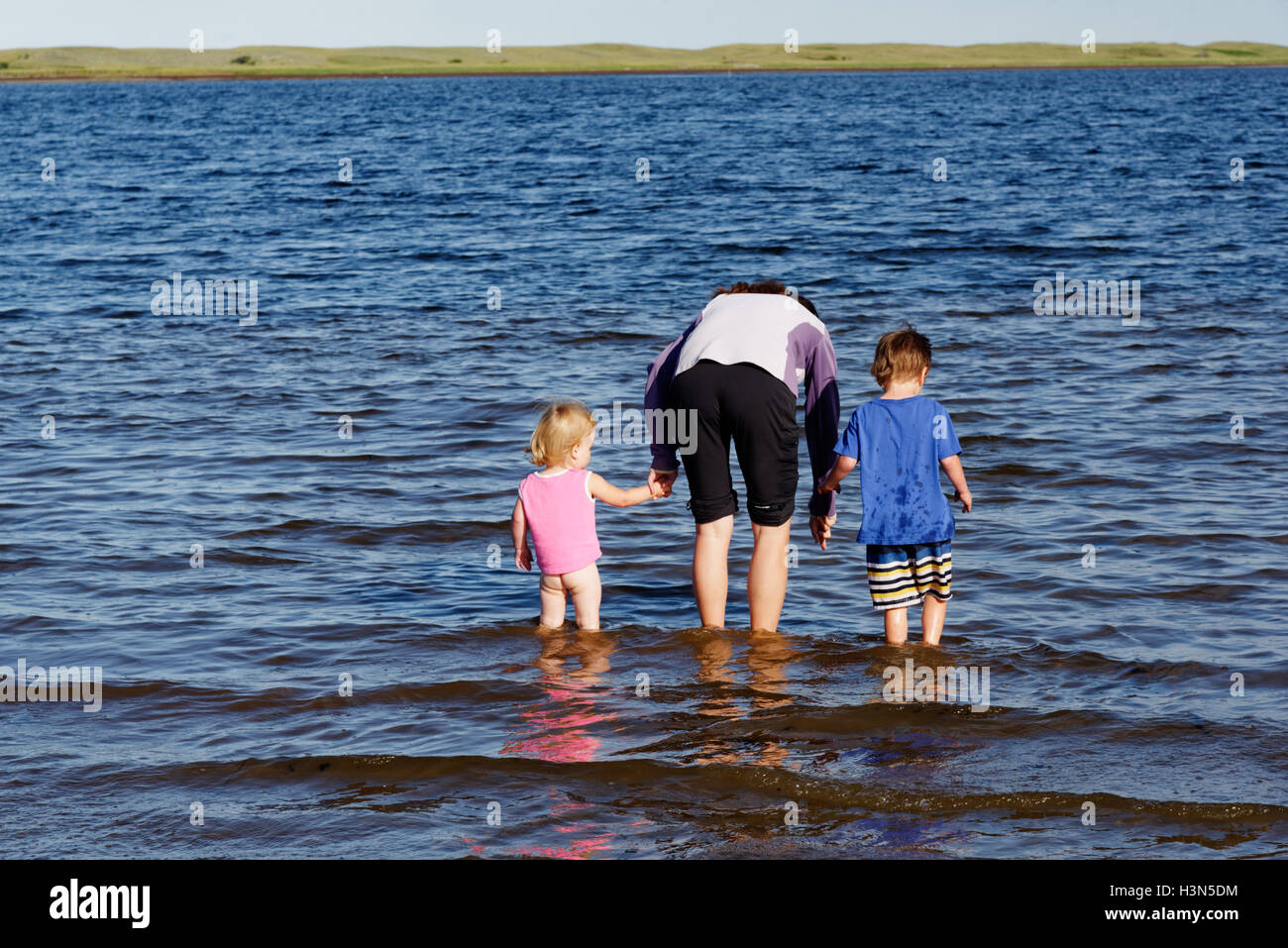 A mother & 2 children (2 and 4 yrs old) paddling & looking for fish in St Louis Lagoon Kouchibouguac National Park New Brunswick Stock Photo