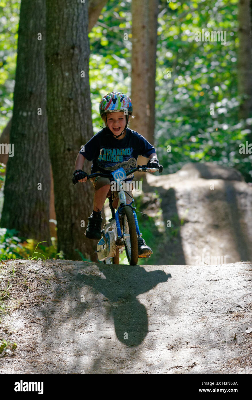 A young (4 year old) boy riding his bike in the wood on a mountain bike pump track Stock Photo