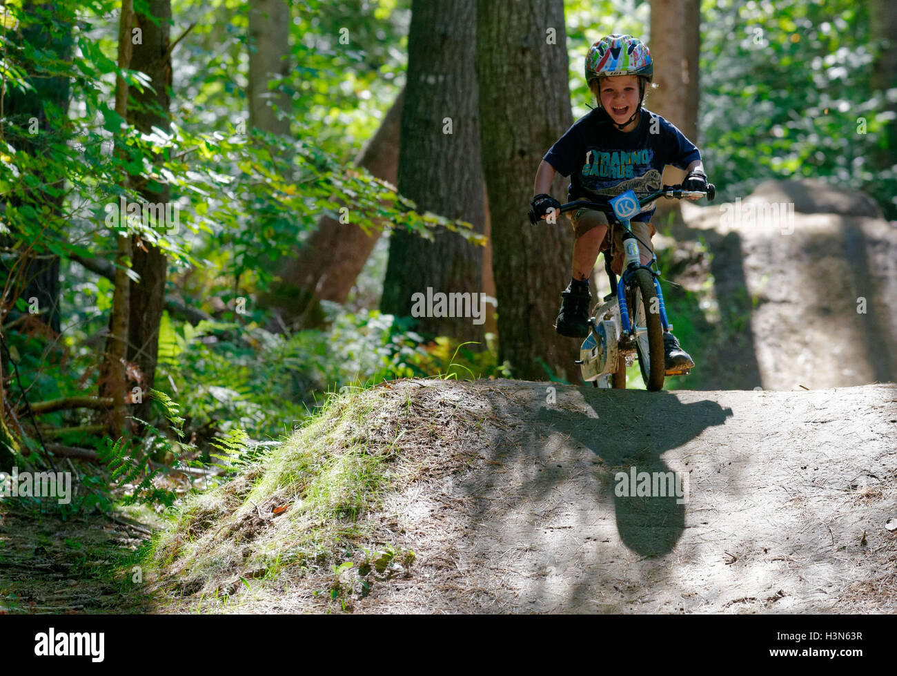 A young (4 year old) boy riding his bike in the wood on a mountain bike pump track Stock Photo