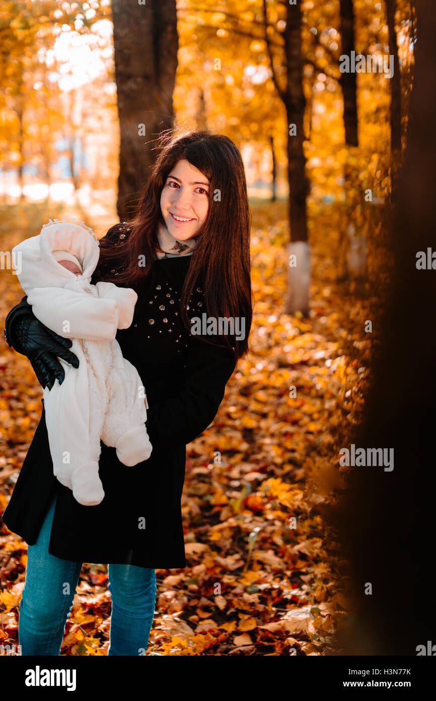 Young mother with her little baby on hand in autumn park Stock Photo ...
