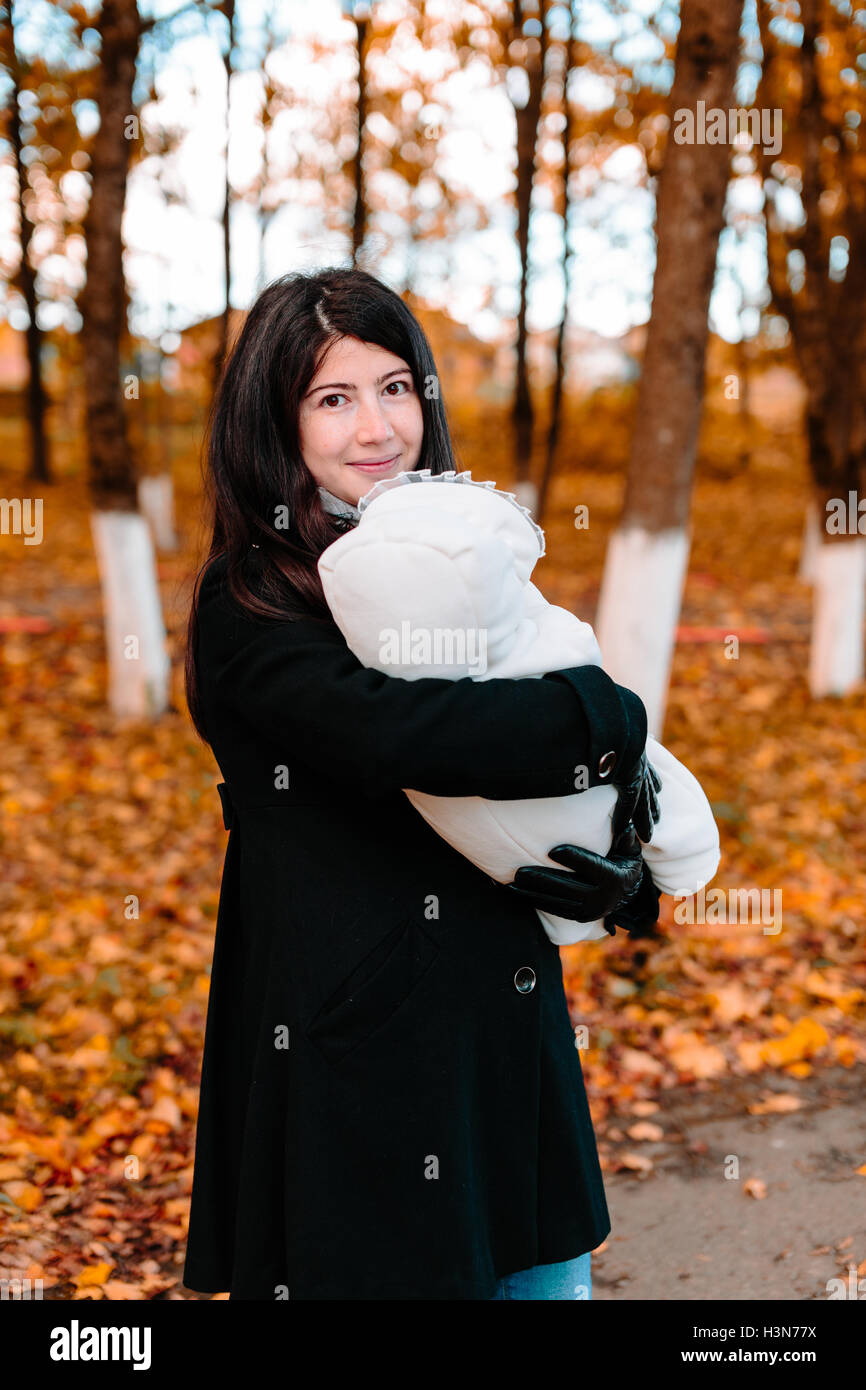 Young mother with her little baby on hand in autumn park Stock Photo ...