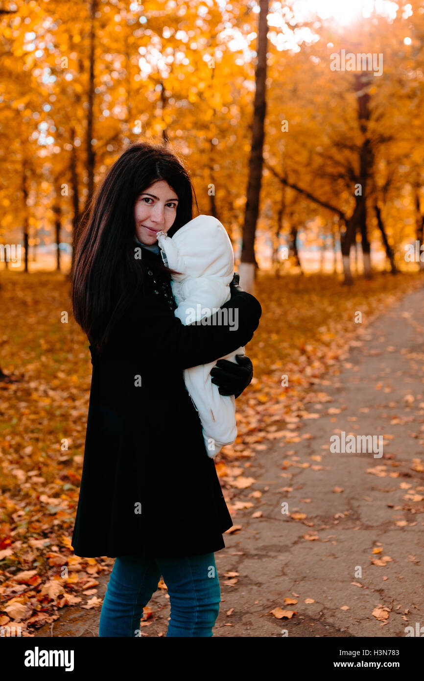 Young mother with her little baby on hand in autumn park Stock Photo ...
