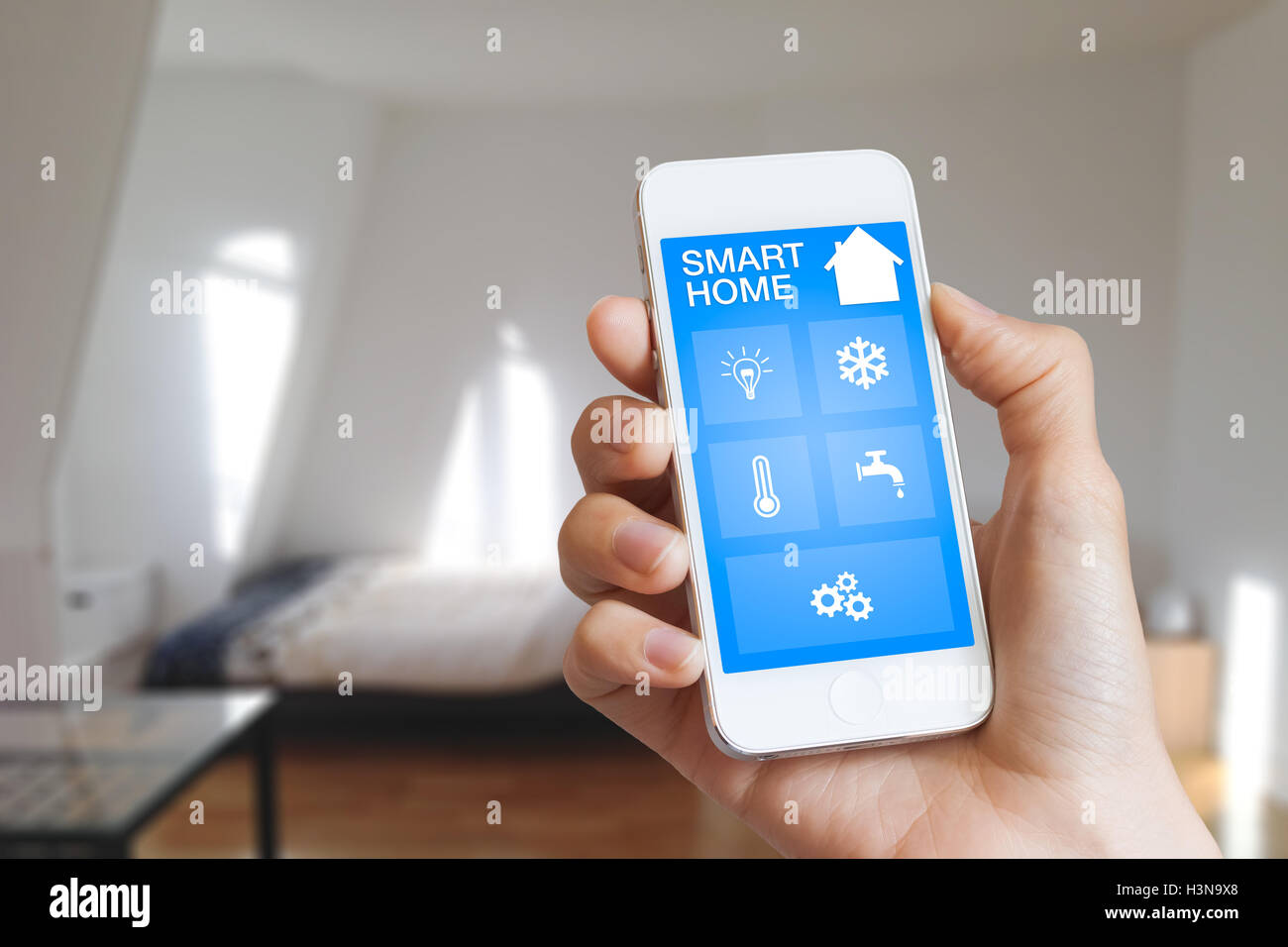 Smart home automation app on smartphone hold by female’s hand with home interior in background Stock Photo