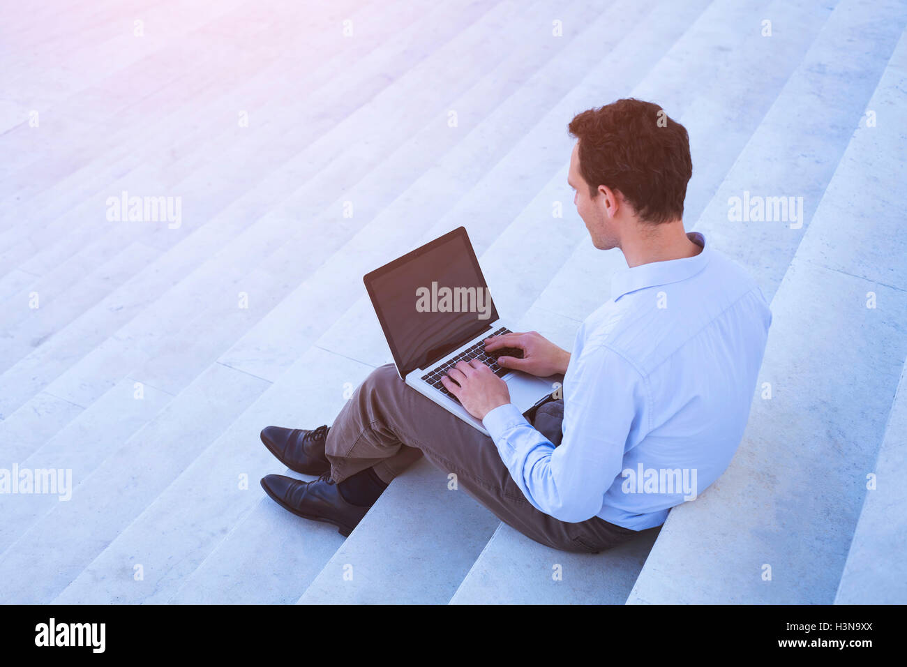 Young adult using laptop outdoors Stock Photo