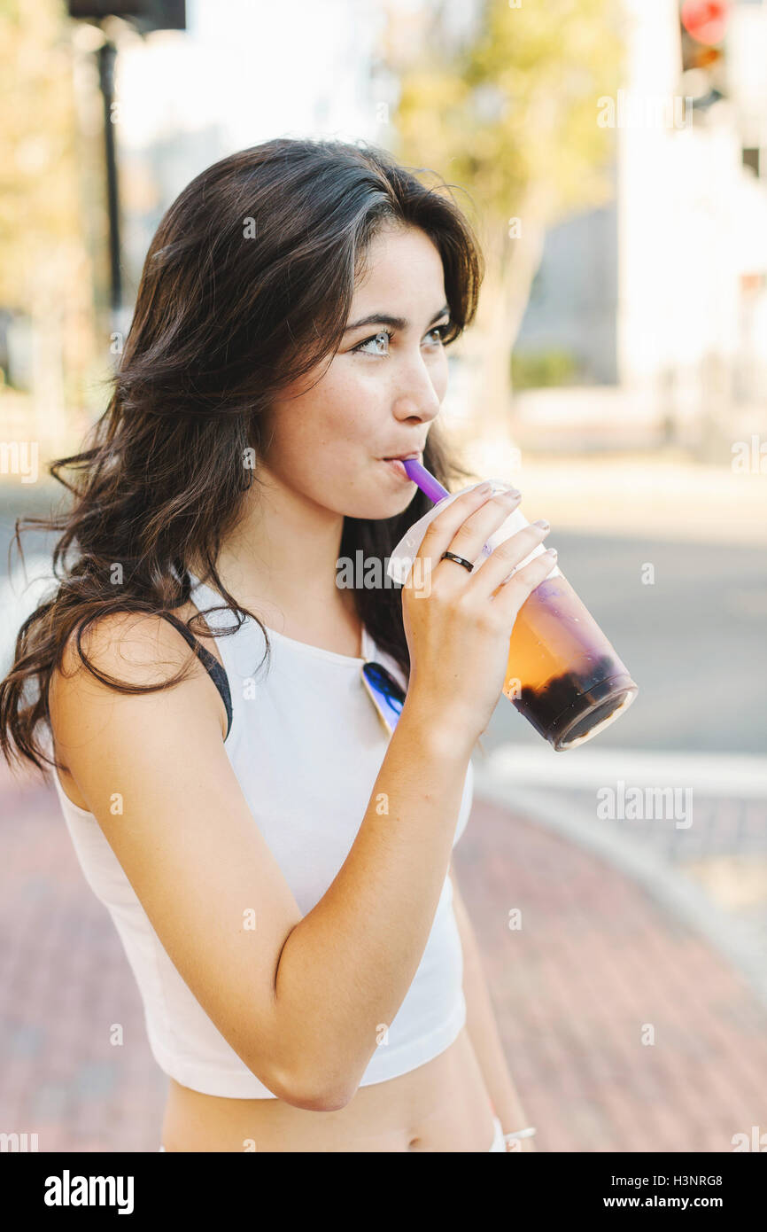 Young woman sipping cold drink on street Stock Photo