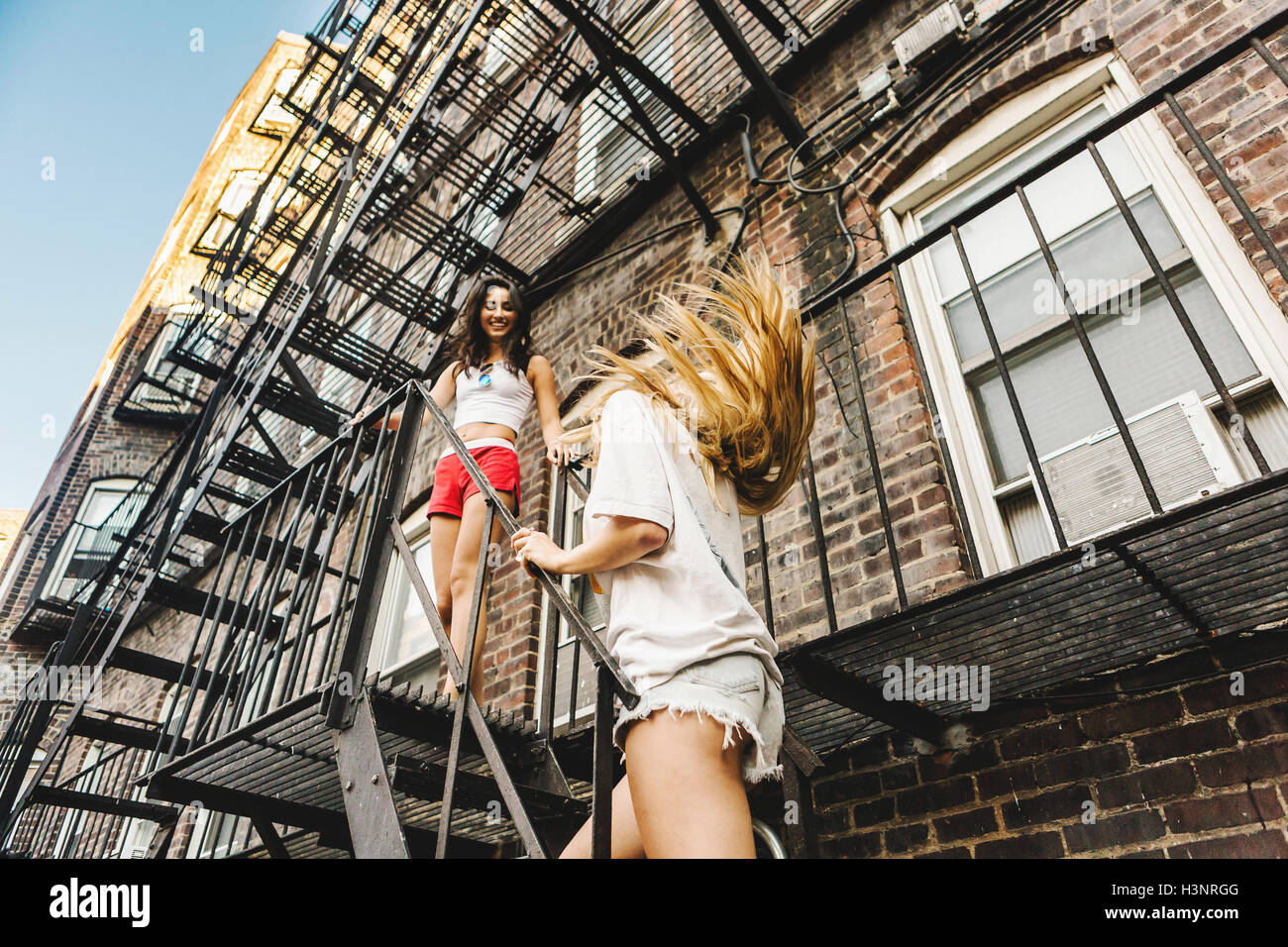 Women climbing fire escape ladder of apartment building, Boston, MA, USA Stock Photo