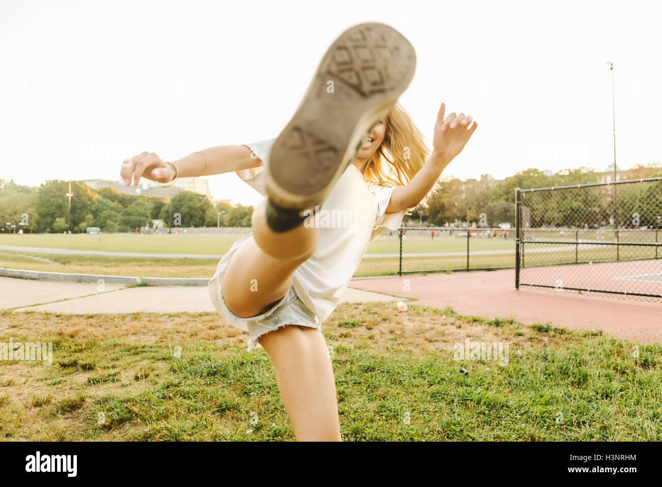 Woman kicking up leg on sports field Stock Photo
