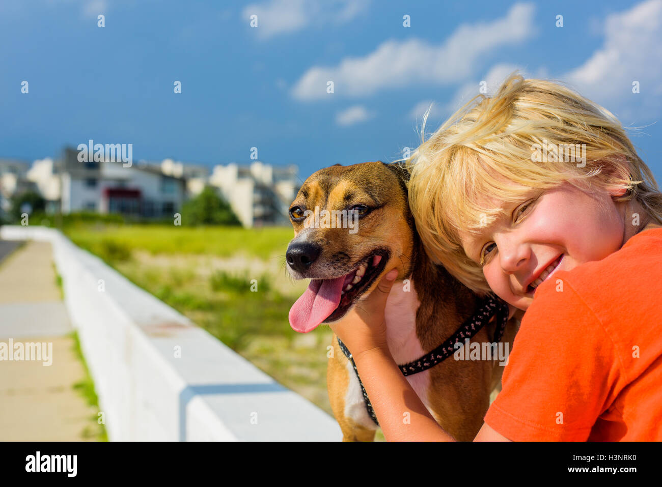 Portrait of young boy outdoors, hugging pet dog Stock Photo