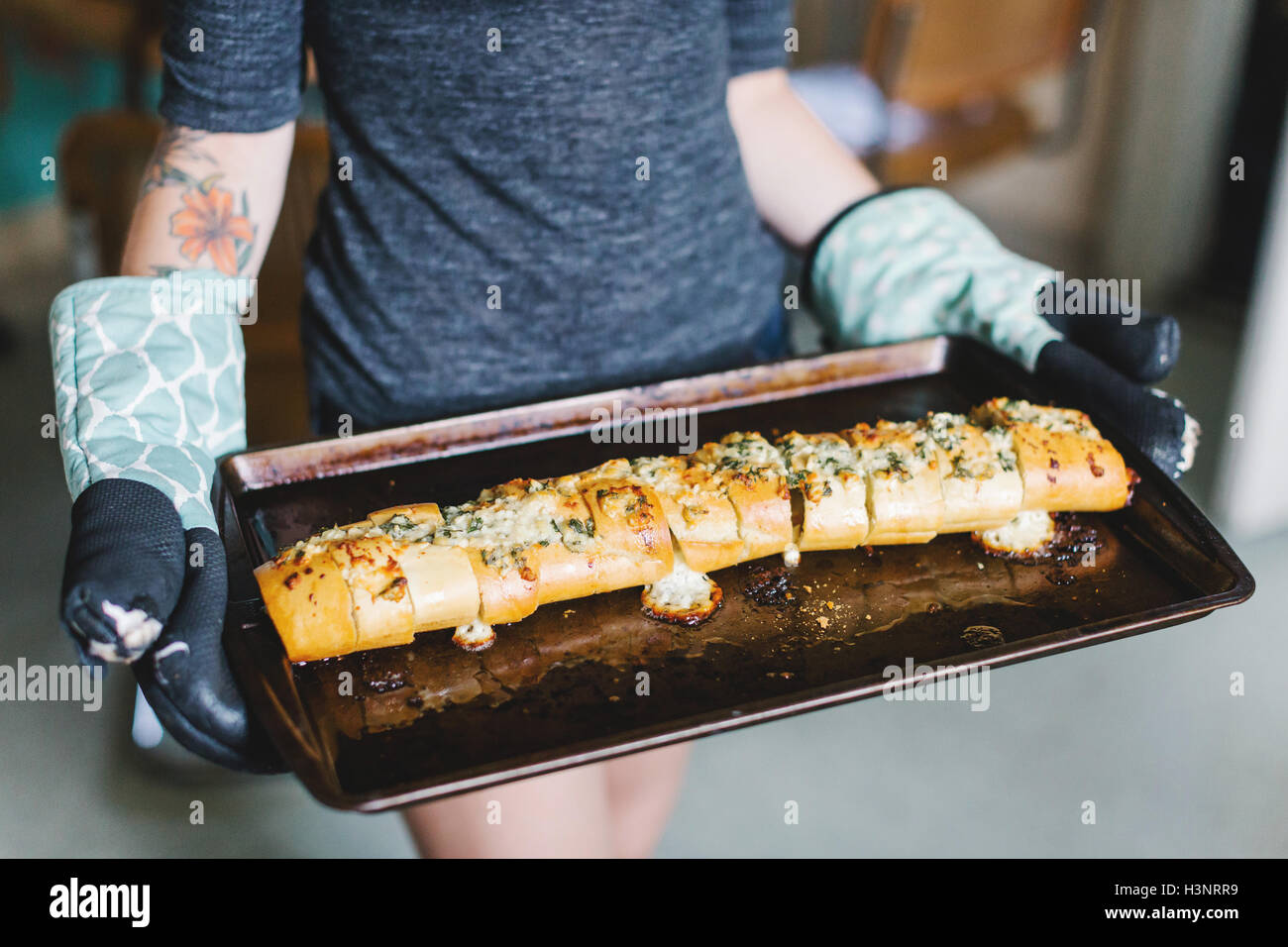 Mid section of young women holding stuffed baguette on baking tin Stock Photo