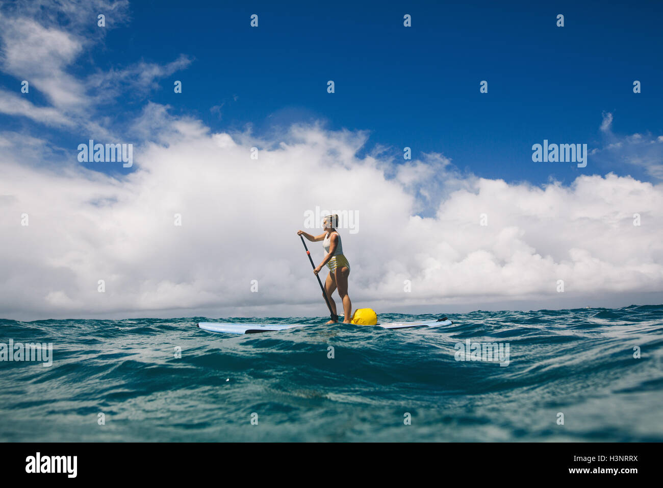 Pregnant mid adult woman stand up paddleboarding in sea, Makua beach