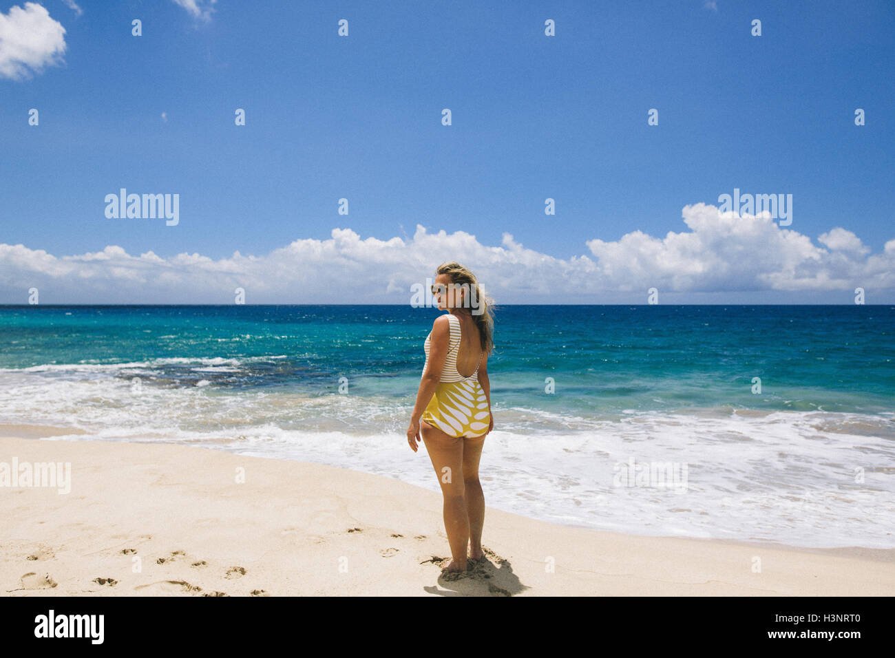 Pregnant mid adult woman wearing swimming costume looking back from Makua beach, Hawaii, USA Stock Photo