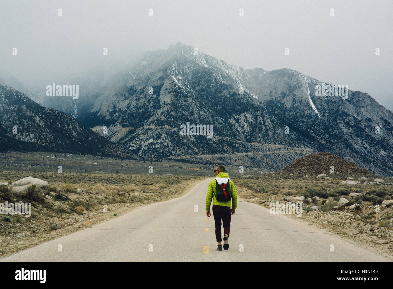 Rear view of hiker on road by mountains, Lone Pine, California, USA Stock Photo