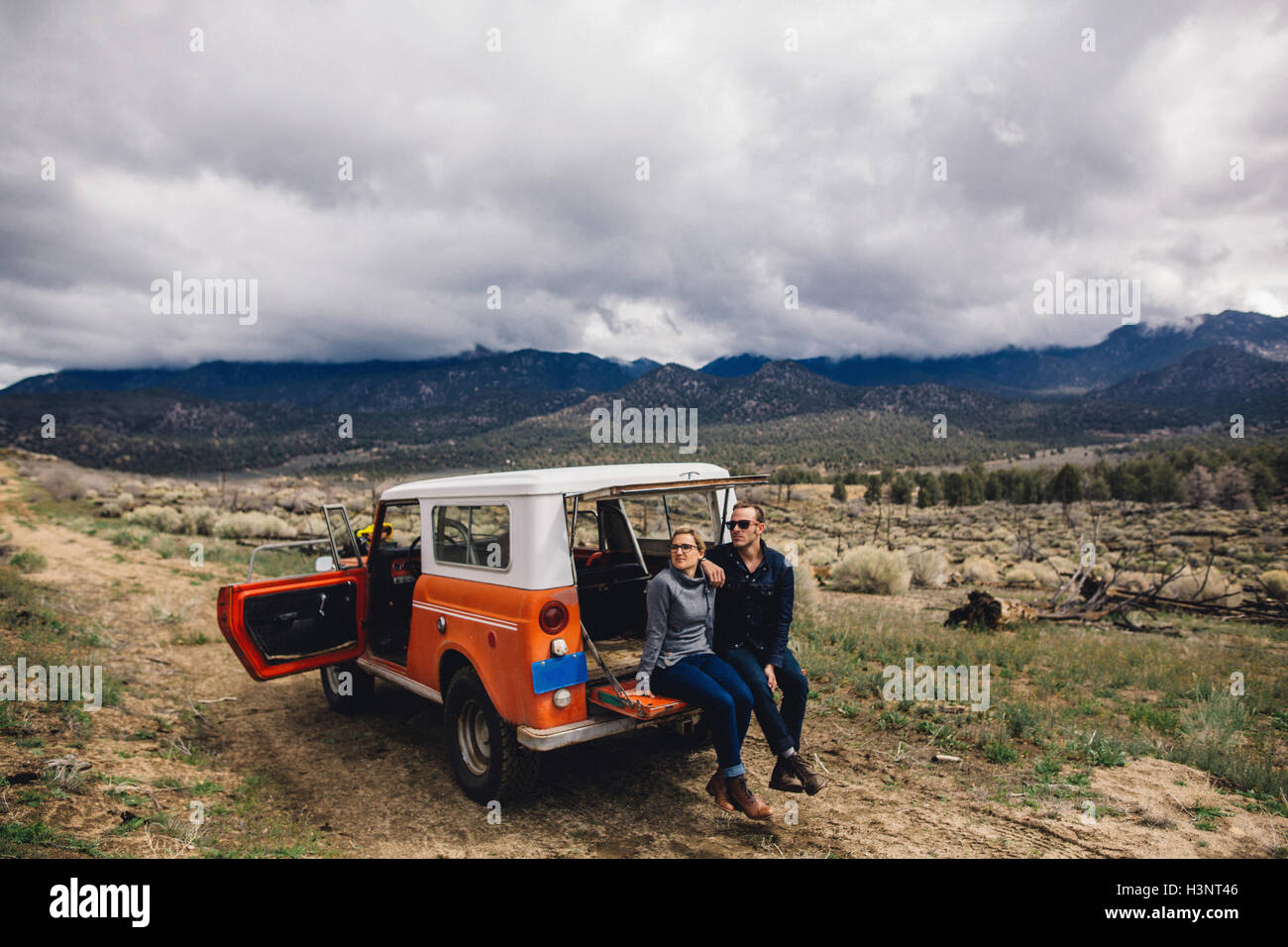 Couple with vehicle on scrubland by mountains, Kennedy Meadows, California, USA Stock Photo