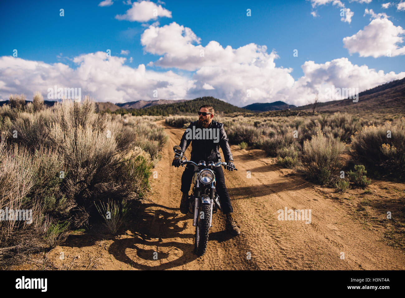 Motorcyclist sitting on motorbike looking away, Kennedy Meadows, California, USA Stock Photo