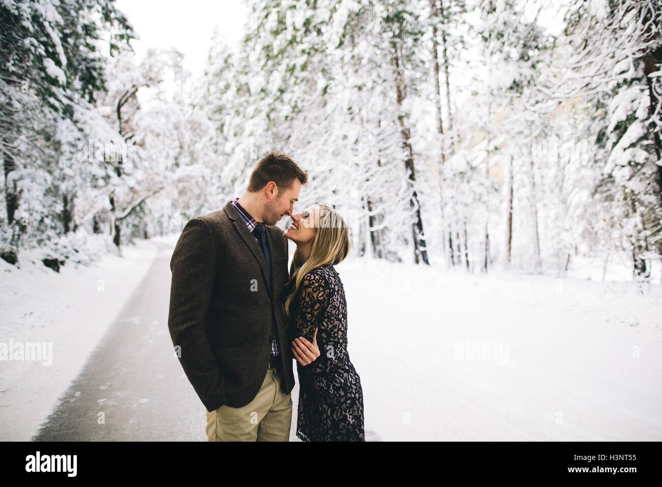 Couple in snow-covered forest face to face smiling Stock Photo