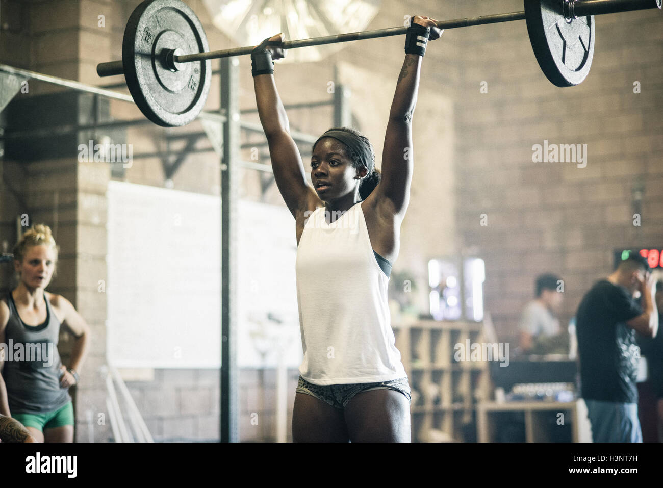 Cross training athlete lifting barbell in gym Stock Photo