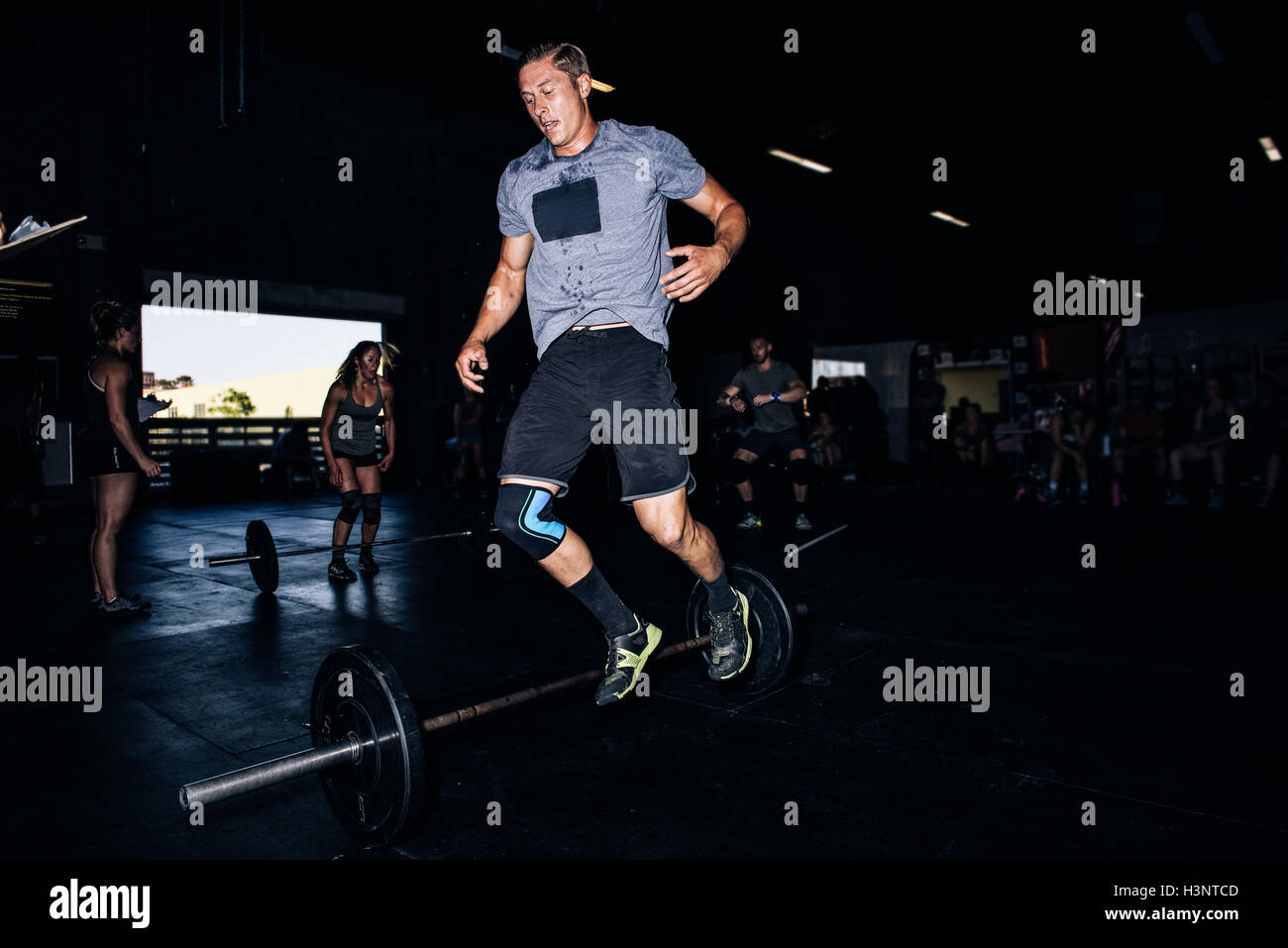 Cross training athlete jumping over barbell in gym Stock Photo Alamy