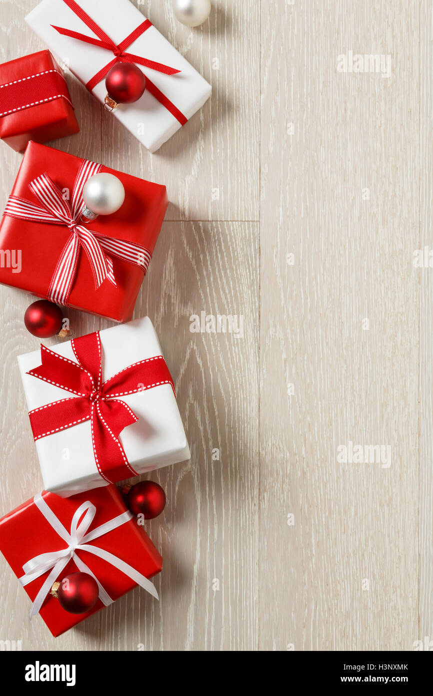 Christmas gifts presents on rustic wood background. Red and white wrapped gift boxes with ribbon bows. Stock Photo