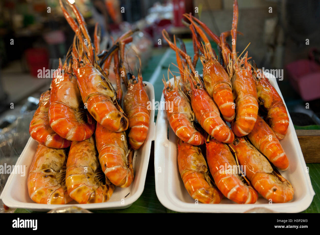 Barbecued or grilled black tiger prawns for sale in styrofoam containers at Or Tor Gor market in Bangkok. Stock Photo