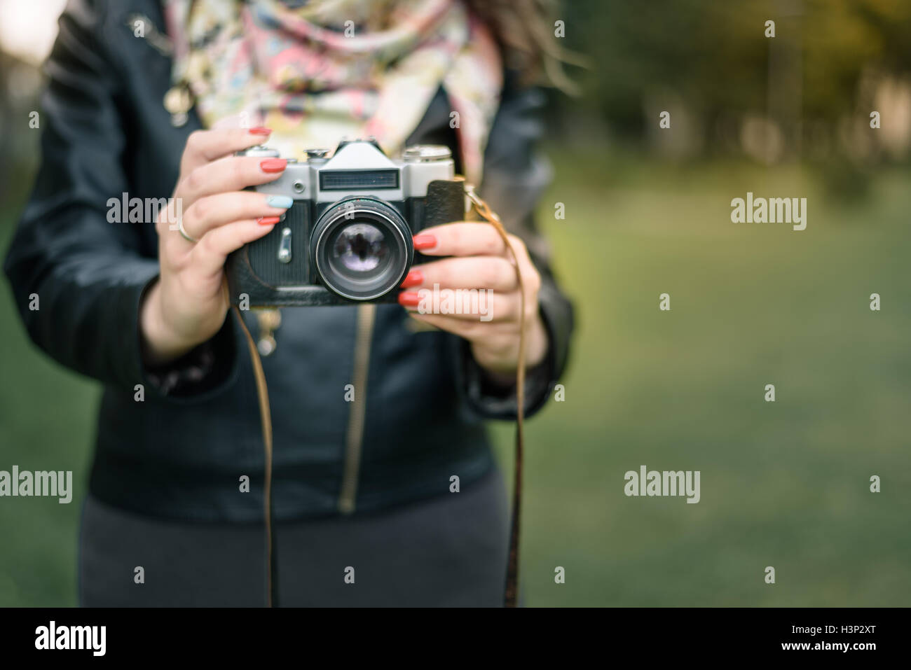 Woman hand holding retro camera close-up on the background of autumn Park Stock Photo