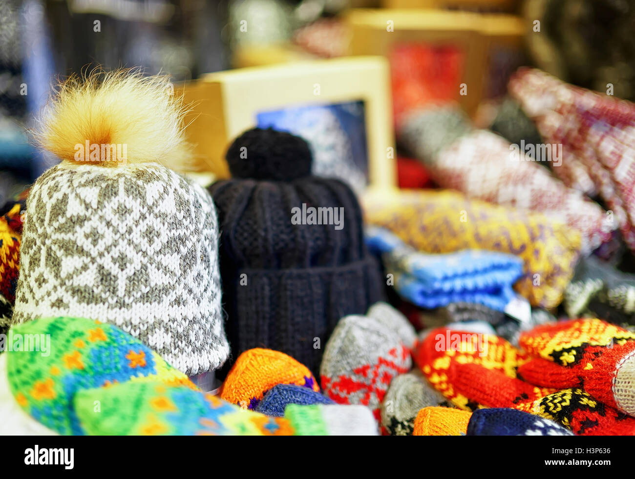 Two warm hats among other knitted clothes displayed for sale at the Christmas market in old Riga, Latvia. At this stand people can also buy festive mittens, gloves, scarfs and little toys for kids. Stock Photo