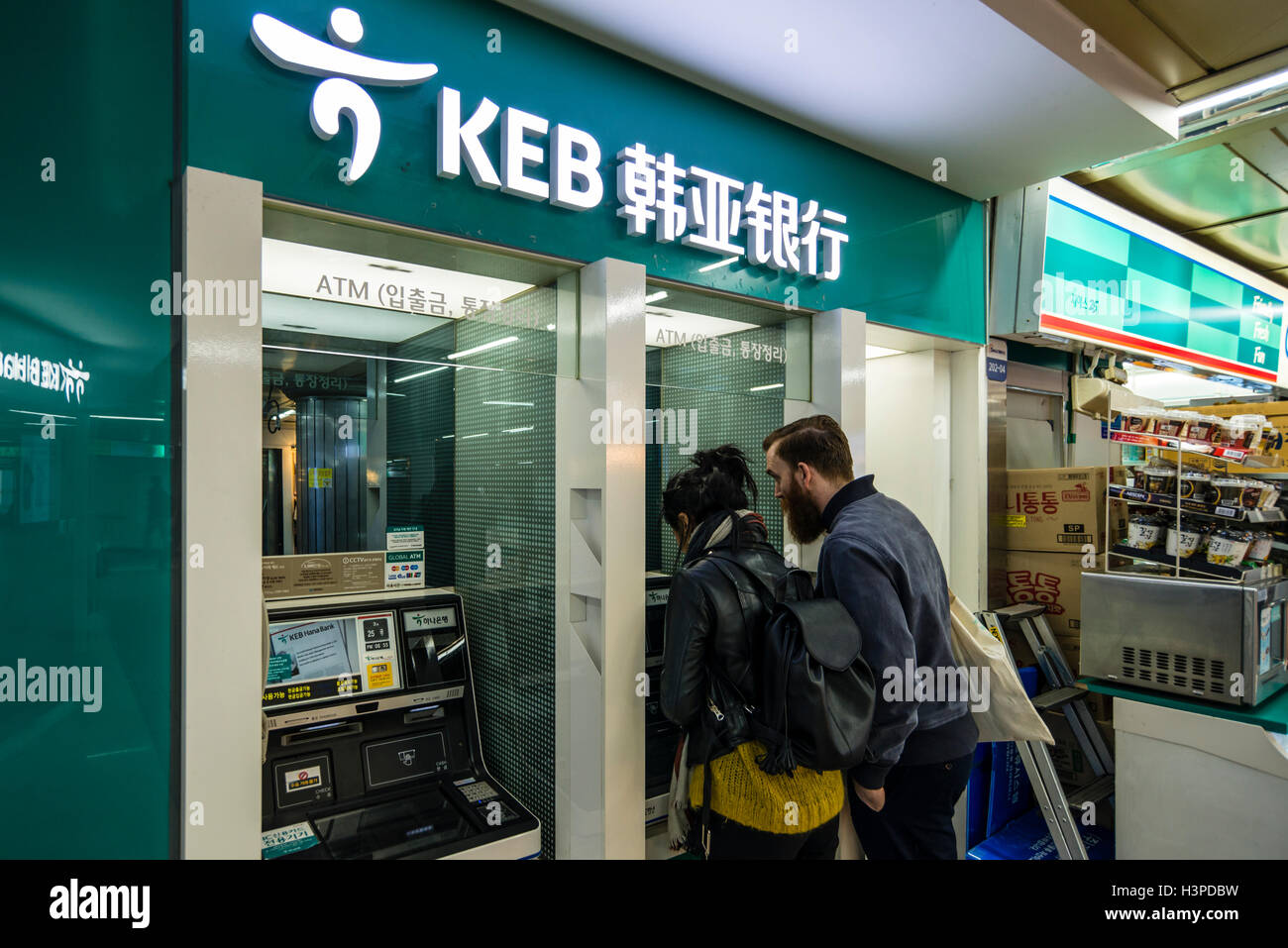European male and female using ATM machine, Seoul, Korea Stock Photo